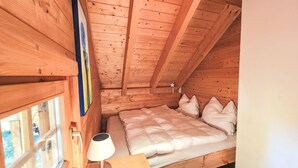 A wooden cabin room with a bed, a nightstand, a lamp, and a window. - Zirbenwaldhütt´n by Interhome (Turracher Höhe)