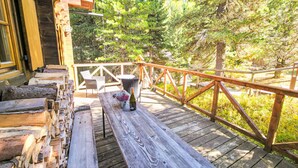 A wooden deck with a table and chairs, surrounded by trees. - Zirbenwaldhütt´n by Interhome (Turracher Höhe)