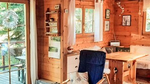 A cozy cabin interior with a wooden dining table, a rocking chair, and a small kitchenette. - Zirbenwaldhütt´n by Interhome (Turracher Höhe)
