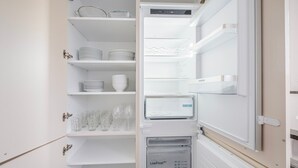 A modern kitchen with a built-in refrigerator and freezer, stainless steel appliances, and white cabinetry. - Blueground | Dietikon, balcony, nr Lindenplatz (Zurich)