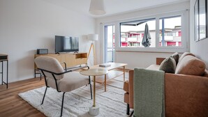 Una sala moderna con televisor, sofá y comedor.