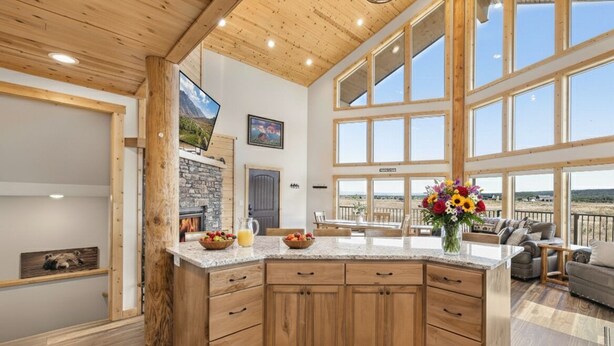 A spacious kitchen with wooden cabinets, a granite countertop, and large windows offering a view of the outdoors. - Eagle Eye Retreat: AC, EV, Hot tub, Minutes to reservoir, 35 miles to W Yellowstone (Island Park)