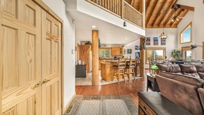 A spacious living area with a high ceiling, wooden beams, a large brown leather sofa, and a dining area with wooden furniture. - HENRYS REEL RETREAT: Private Beach Dock on Henrys Lake Garage Yellowstone (Island Park)