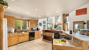 A spacious kitchen with wooden cabinets, a built-in oven, and a large island with a sink. - HENRYS REEL RETREAT: Private Beach Dock on Henrys Lake Garage Yellowstone (Island Park)