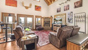 A spacious living room with leather sofas, a fireplace, artwork on the walls, and large windows. - HENRYS REEL RETREAT: Private Beach Dock on Henrys Lake Garage Yellowstone (Island Park)