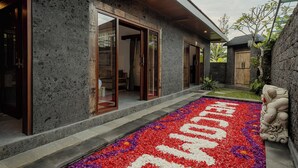 Una casa moderna con fachada de piedra, grandes puertas correderas de vidrio y un jardín cuidado.