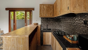 Una cocina moderna con gabinetes de madera, encimera negra y salpicadero de azulejos.