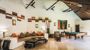 Eine großzügige Lounge mit Billardtisch, gemütlicher Sitzgelegenheit und Kunstwerken an den Wänden.