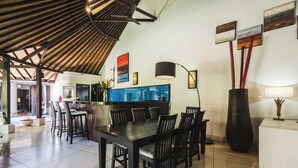 Ein großzügiger Essbereich mit einem großen Tisch und Stühlen, eine Bar mit Hockern und ein modernes Decken-Design.