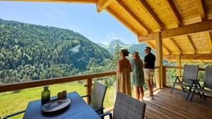 A wooden deck with a table and chairs overlooking a mountainous landscape. - Apartment in Abondance Valley With Jacuzzi (Abondance)
