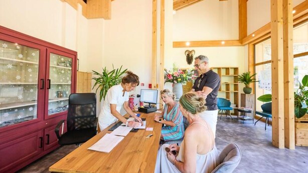 A wooden interior with a red cabinet, a computer, and people engaged in a meeting. - Apartment in Abondance Valley With Jacuzzi (Abondance)
