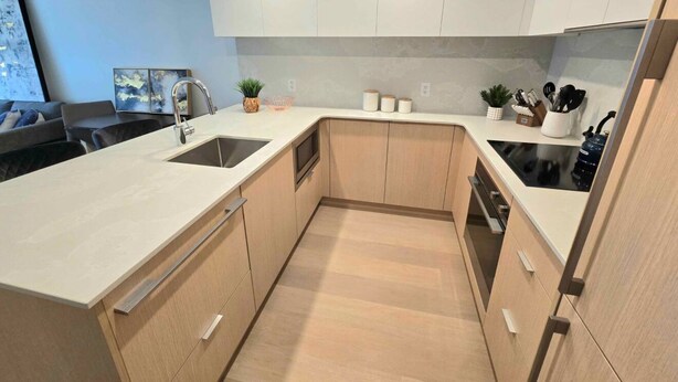 Une cuisine moderne avec des meubles en bois clair, un plan de travail blanc et un lave-vaisselle encastré.