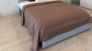 Une chambre à coucher moderne avec un lit, une couverture marron et deux oreillers.