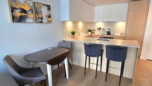 Une cuisine moderne dotée d’un îlot central, de deux tabourets de bar et d’une table à manger avec des chaises.