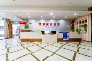 Zona de recepción de un hotel con mostrador, cartel y suelo de baldosas.