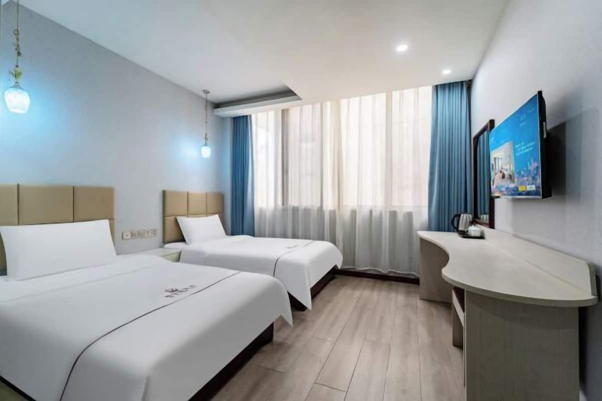 Une chambre d’hôtel avec deux lits, un bureau et une télévision.