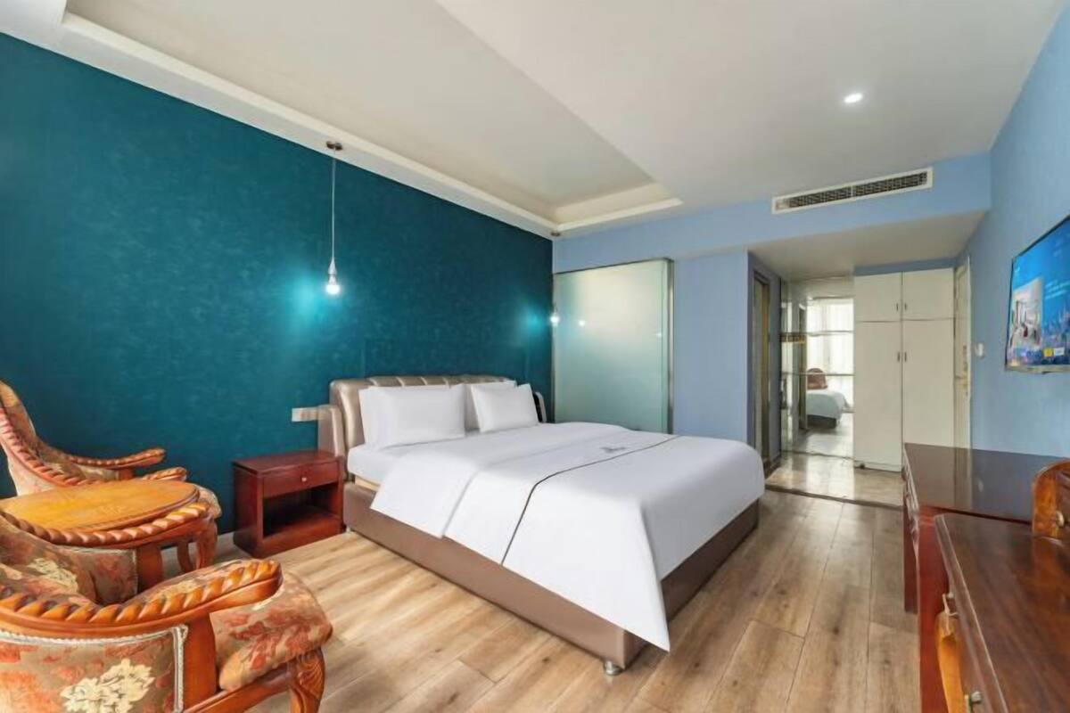 Une chambre à coucher avec un lit, des tables de chevet en bois, une chaise et une commode.