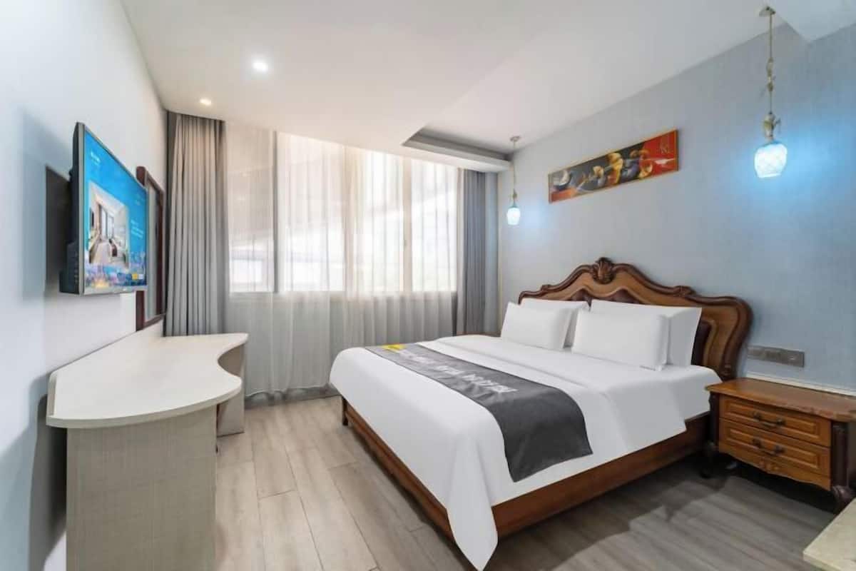 Une chambre d’hôtel avec un lit, un bureau, une télévision et une fenêtre avec des rideaux.