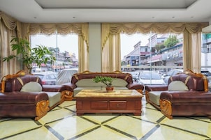 Un hall de hotel con un ventanal grande, un conjunto de sofás, una mesa de centro y una planta en maceta.