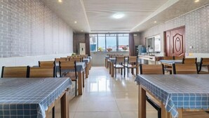 Un comedor amplio con techos altos y paredes de ladrillo, con varias mesas y sillas.