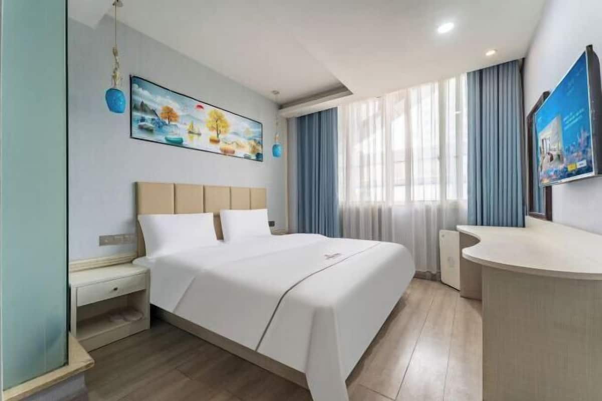 Une chambre d’hôtel équipée d’un lit, d’une table de chevet et d’un espace bureau.
