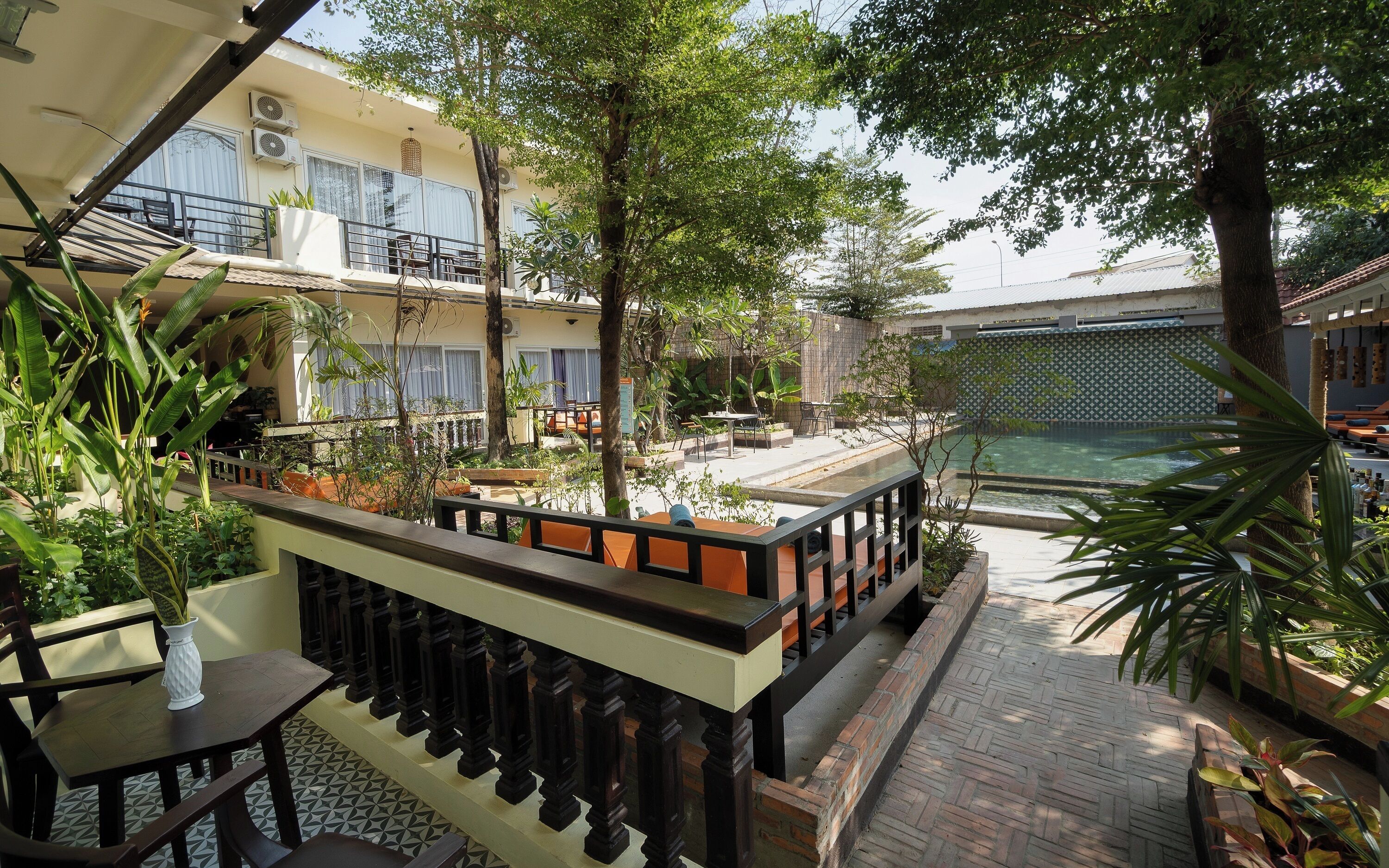 Una terraza en la azotea con mobiliario exterior, piscina y abundante vegetación.