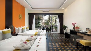 A hotel room with two beds, a balcony, a desk with a chair, and a dining table with chairs.