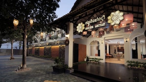 The exterior of Indochine Sanctuary with a well-lit entrance, a tiled pathway, and a balcony overlooking the area.