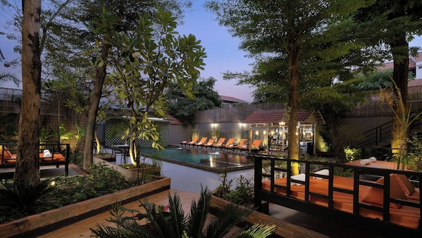 A serene poolside area with lounge chairs, a small pool, and lush greenery.