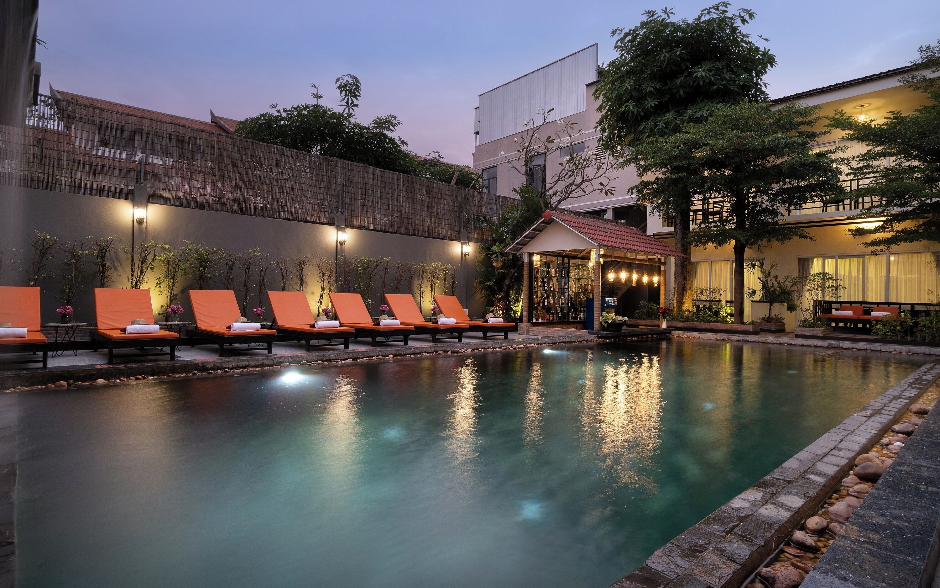 Zona de piscina con sillones reclinables y un bar.