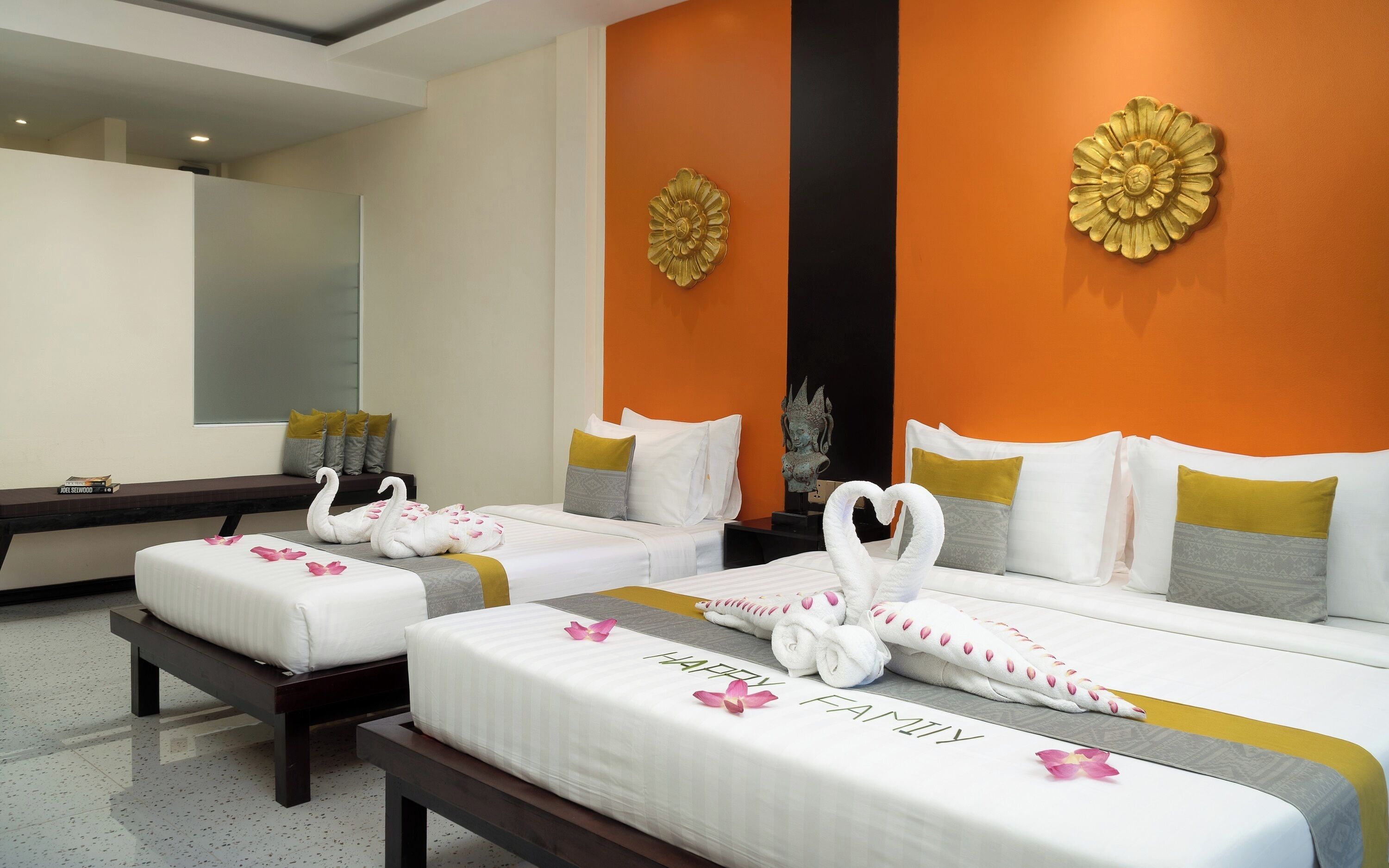 Habitación de hotel con dos camas, cada una decorada con toallas con forma de cisne y una colcha con estampado 'Happy Family'.