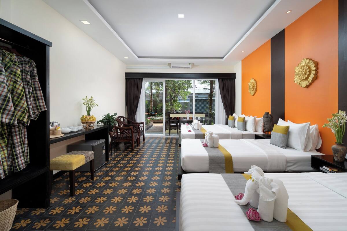 Une chambre d’hôtel avec deux lits, un bureau avec une chaise, une petite table et une vue sur l’extérieur.