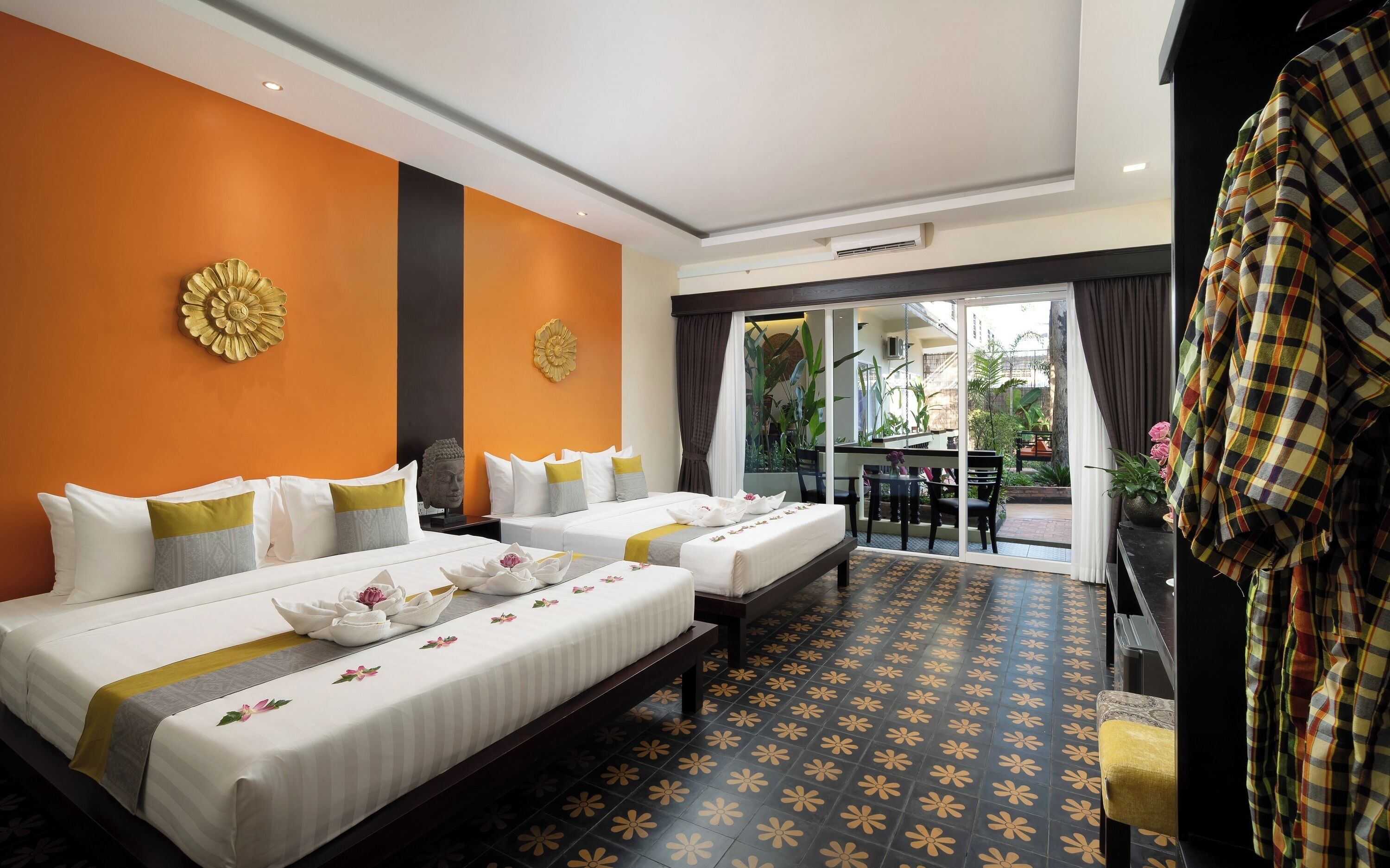 Une chambre d’hôtel avec deux lits, un coin repas et une vue sur le jardin extérieur.