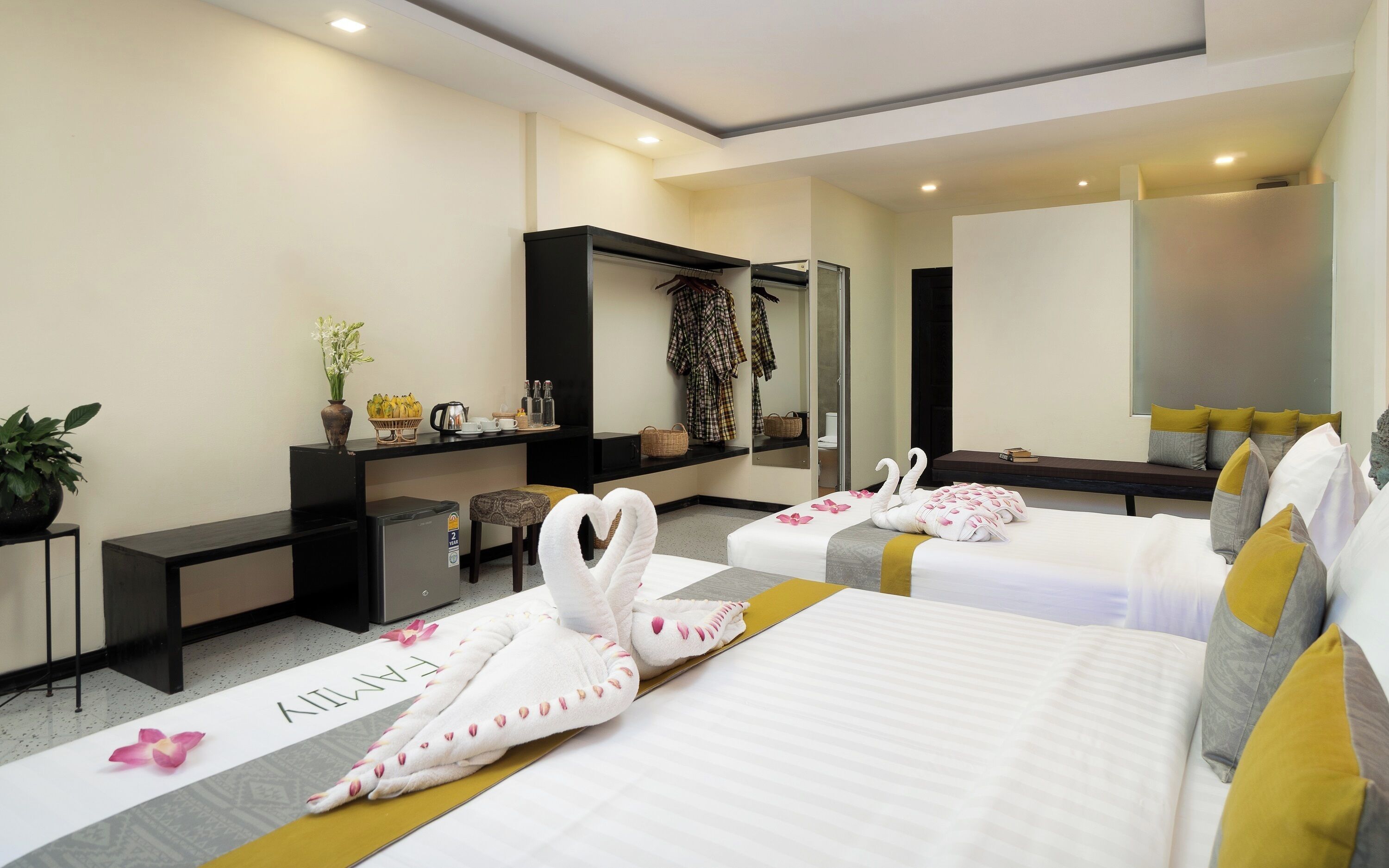 A hotel room with two beds, a desk, a mirror, and a small seating area.