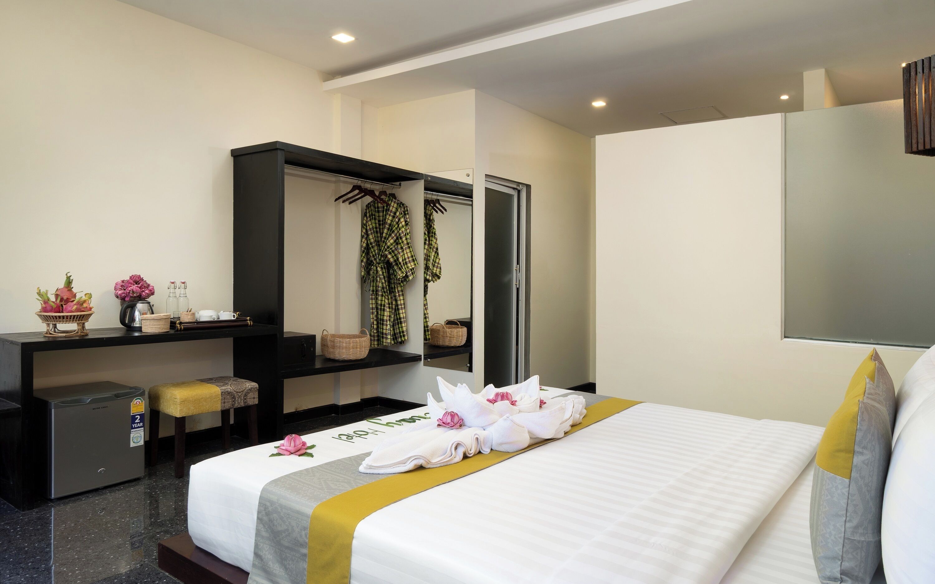 A hotel room with a bed, a desk, a wardrobe, and a mirror.