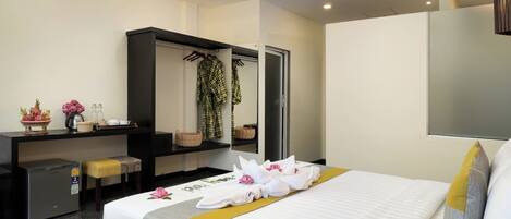 A hotel room with a bed, a desk, a wardrobe, and a mirror.