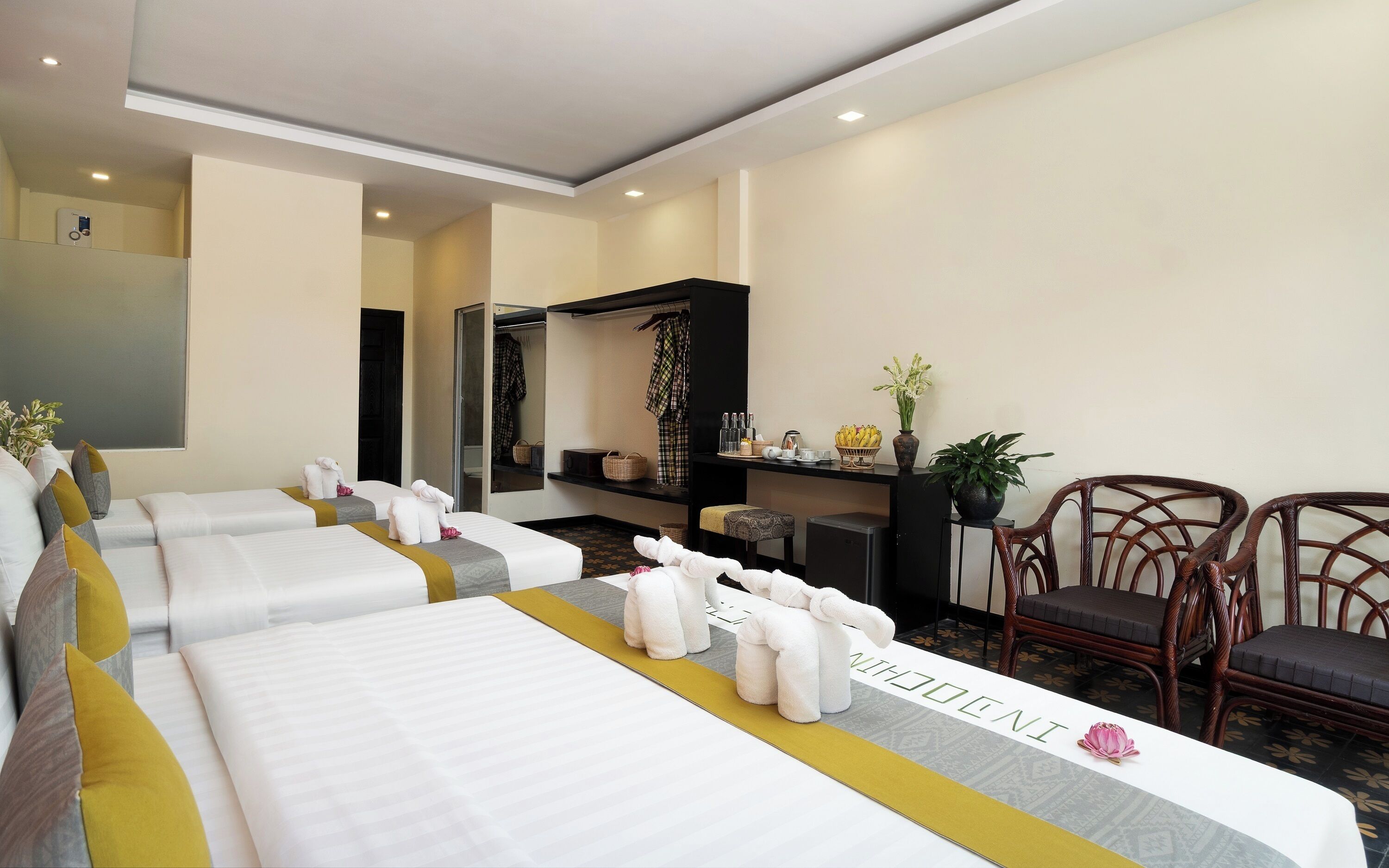 A hotel room with two beds, a desk, a chair, and a mirror.