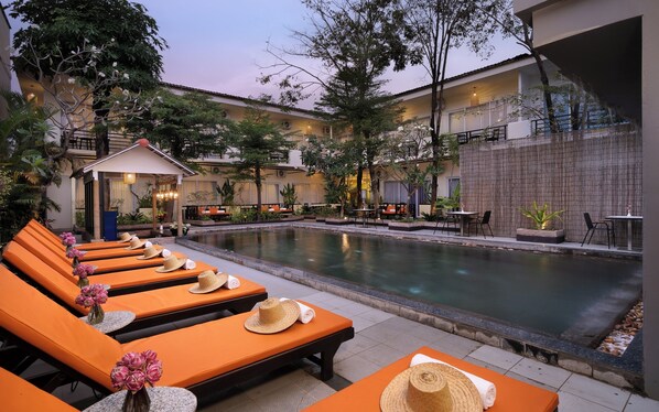 A poolside area with orange loungers, a small gazebo, and a stone wall. -  Indochine Sanctuary Boutique Hotel (Siem Reap)
