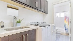 A kitchen with a sink, countertop, cabinets, a dishwasher, and a washing machine. - Sweet Home-Separate Entry-Near YVR Airport & Skytrain & Costco (Greater Vancouver)