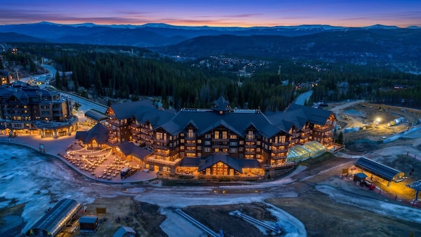 A large lodge with multiple stories, a ski lift, and a dining area with outdoor seating.