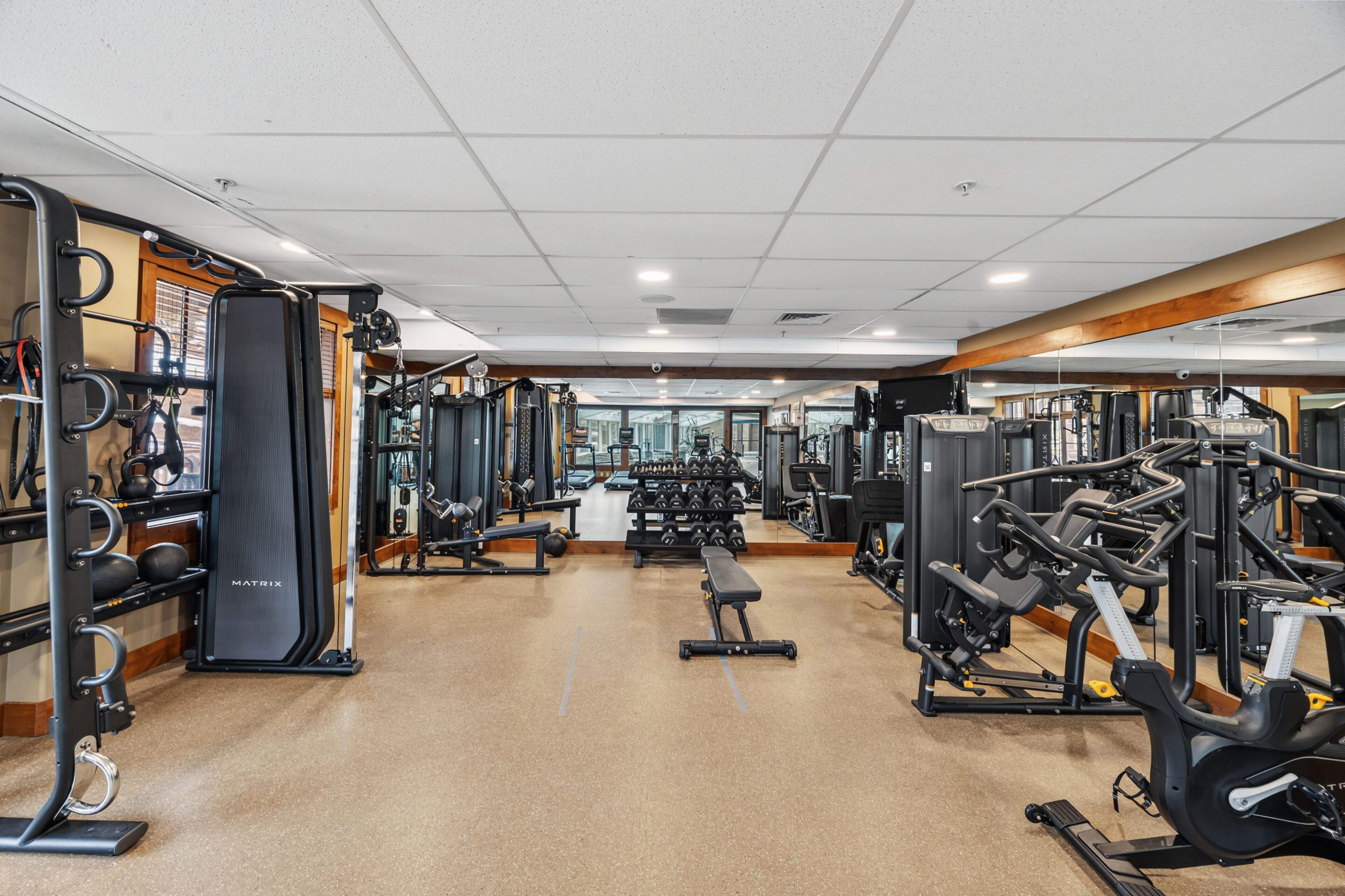 A gym with various exercise equipment, a bench, and a mirrored wall.