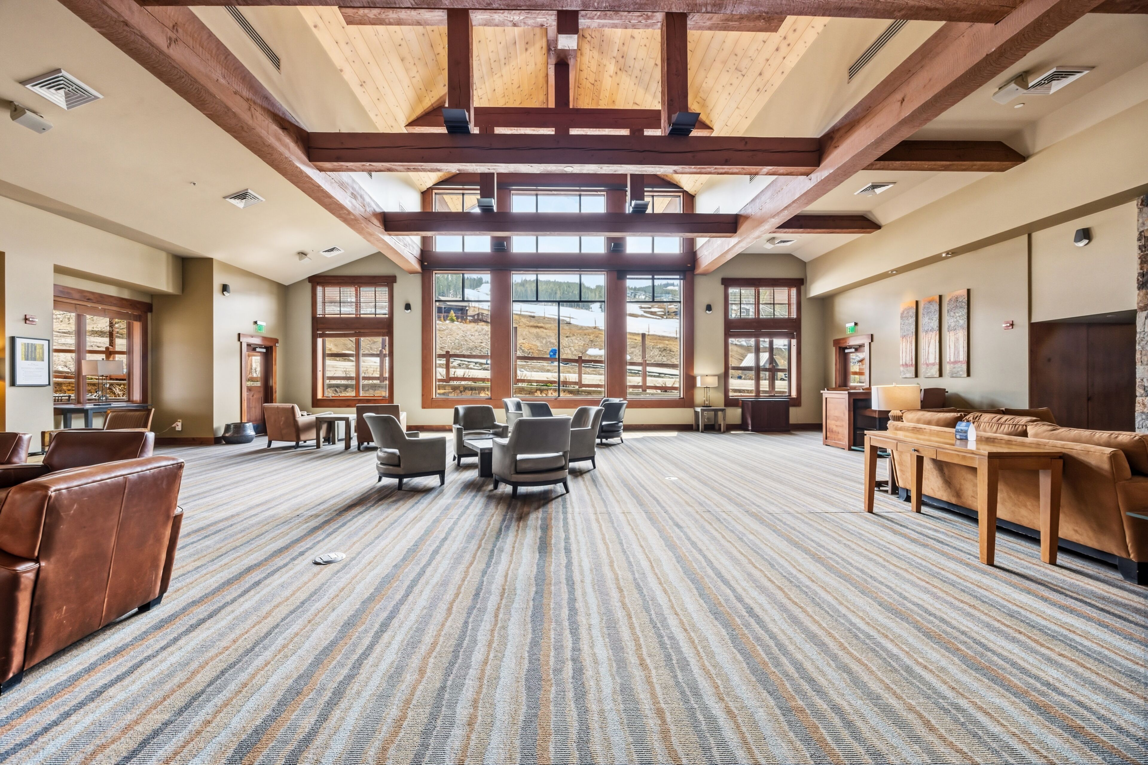 A spacious room with a high ceiling, large windows, and a carpeted floor.