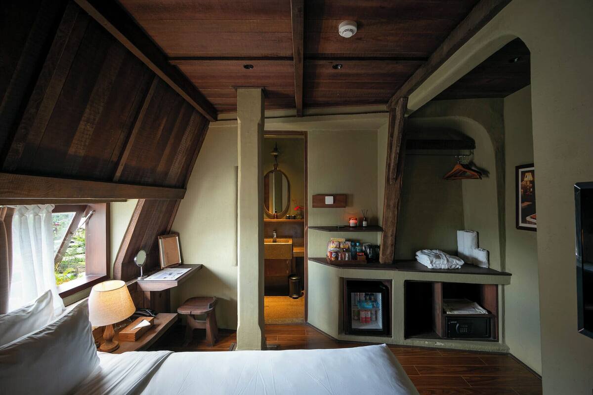 Une chambre avec un lit, un bureau, un miroir et une petite kitchenette.