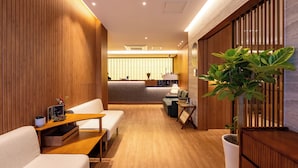 A modern hotel lobby with wooden paneling, a reception desk, seating area, and a large potted plant. - Haeundae Toyu Ryokan (Busan)
