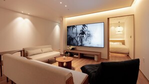 A modern hotel room with a sofa, a black armchair, a coffee table, a TV, and a bed. - Haeundae Toyu Ryokan (Busan)