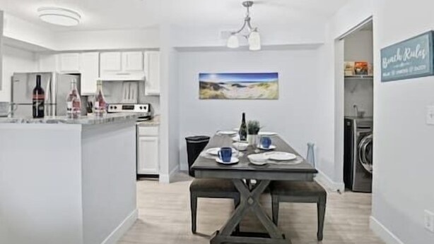 Een moderne keuken met witte kasten, een eethoek met een bank en een schilderij aan de muur.