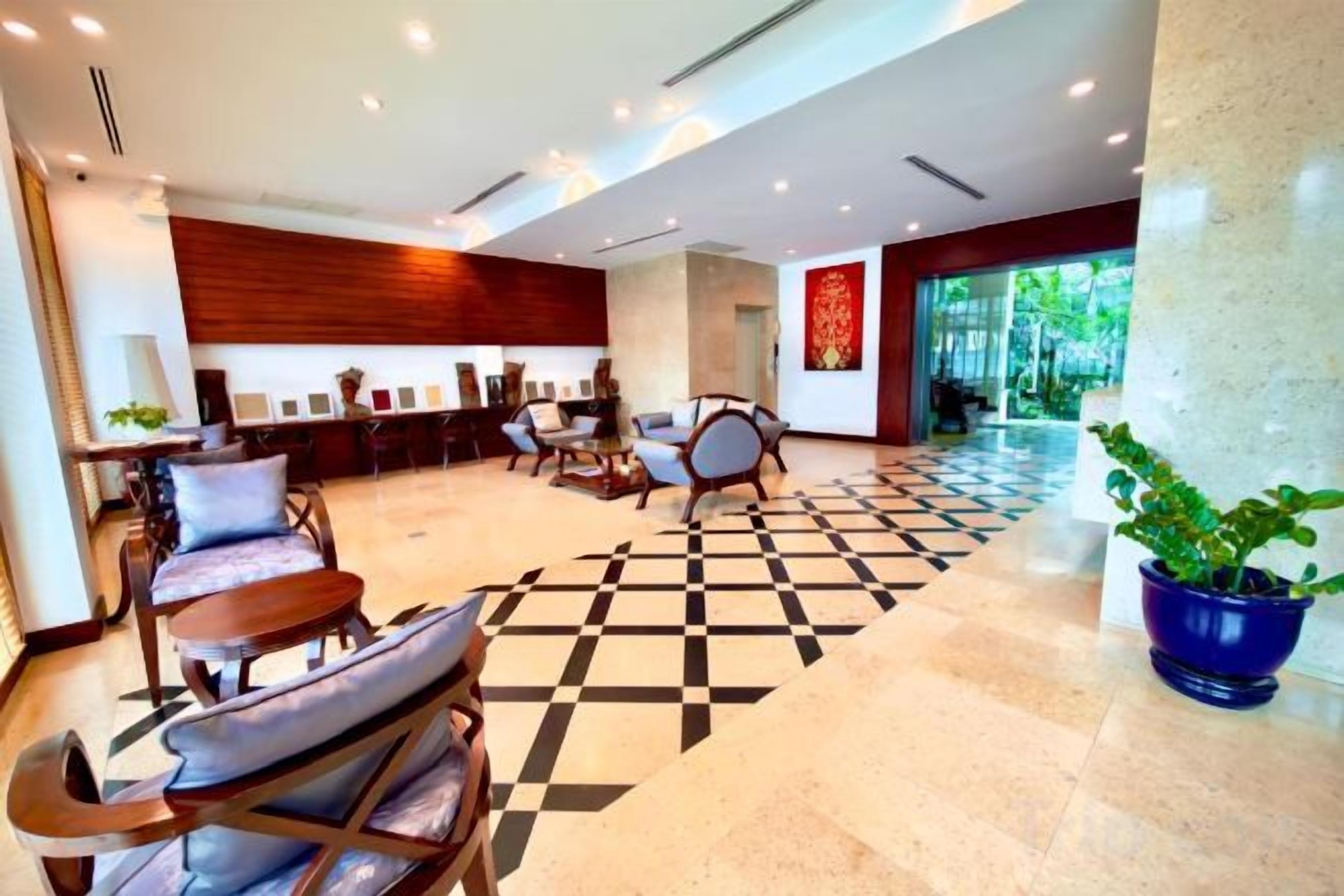 Un vestíbulo de hotel con mostrador de recepción, zona de estar y una gran planta en maceta.