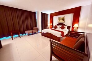 Una camera d'albergo con un letto grande, una sedia, una scrivania e una TV a parete.