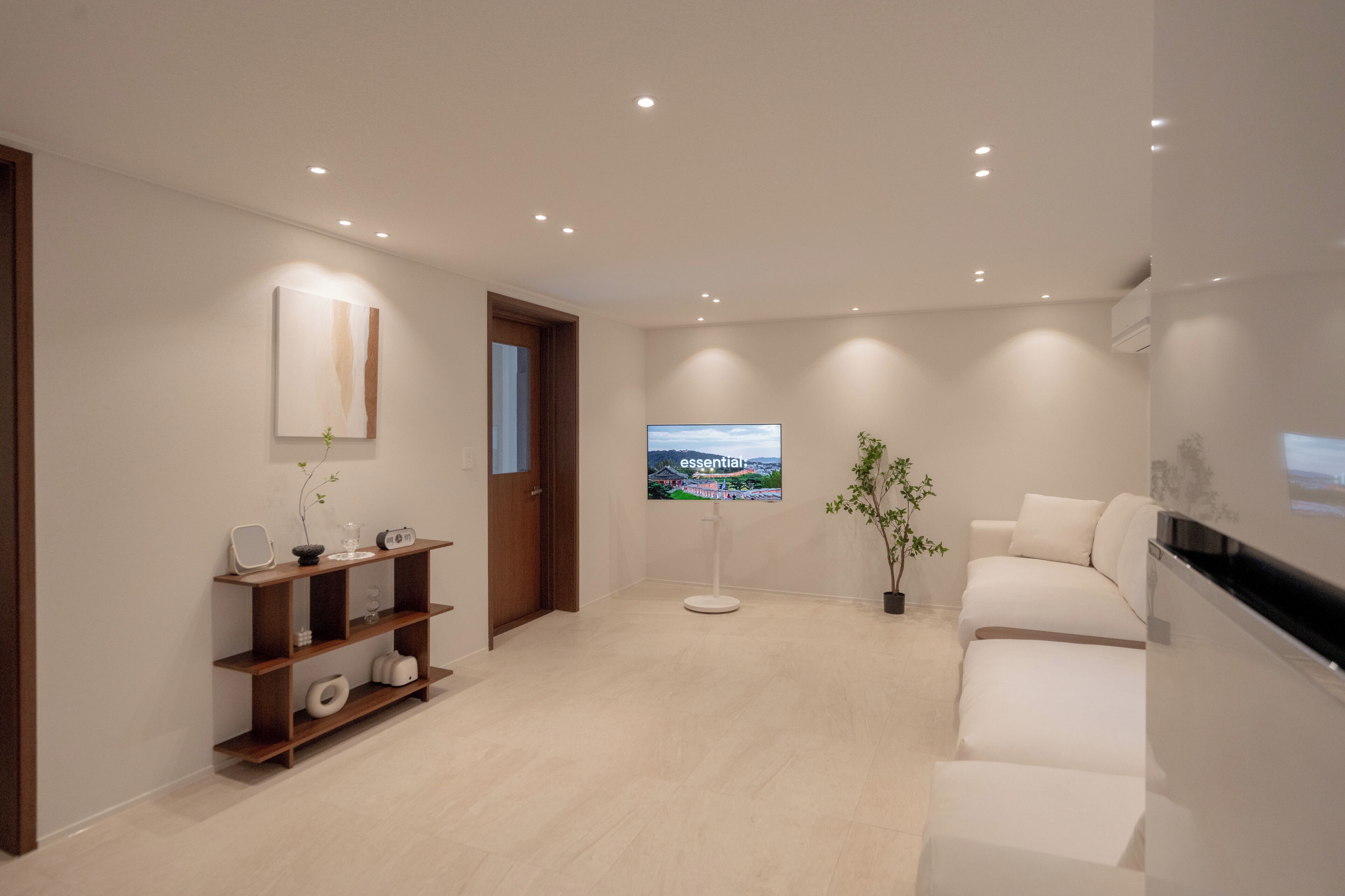 Un moderno vestíbulo de hotel con un mostrador de recepción de madera, un televisor de pantalla plana, un sofá y una planta en maceta.