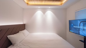 A modern hotel room with a wooden ceiling, a bed with white bedding, and a television on the right side. - Harujae Myeongdong (Seoul)